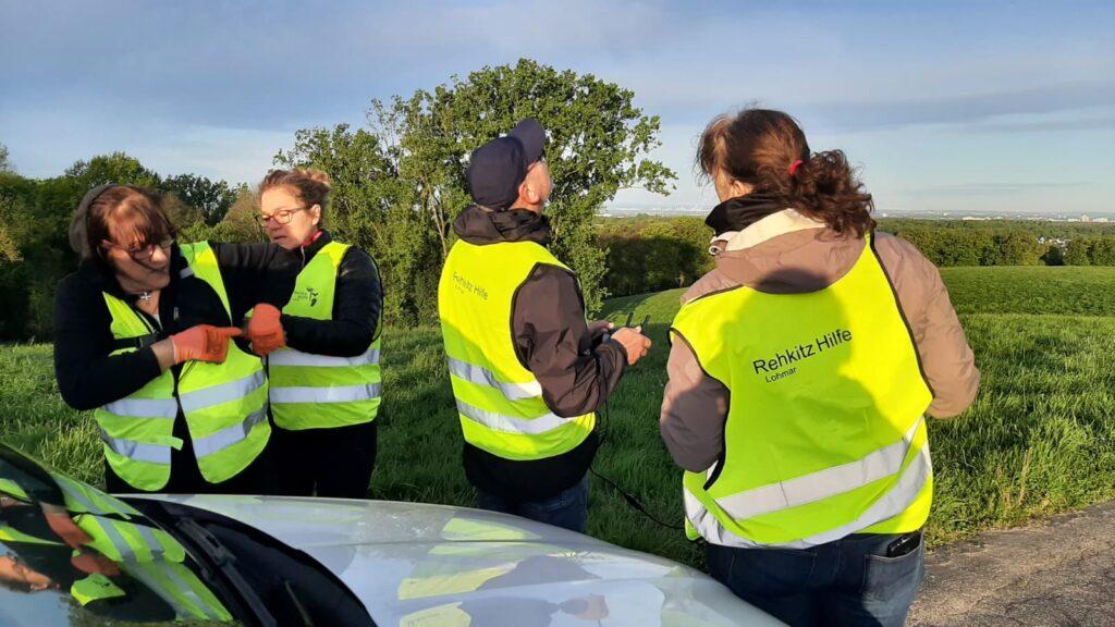 Gruppe von Helfern mit Warnwesten bei der Rehkitzrettung im Feld