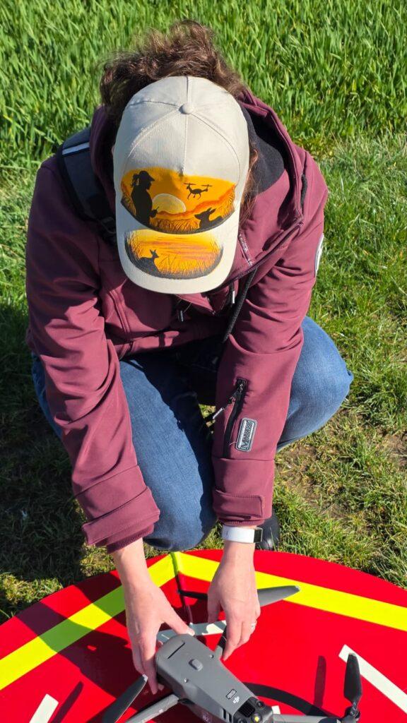 Person bei der Rehkitzrettung startet Drohne im Feld und trägt eine KitzCaps Cap mit Motiv